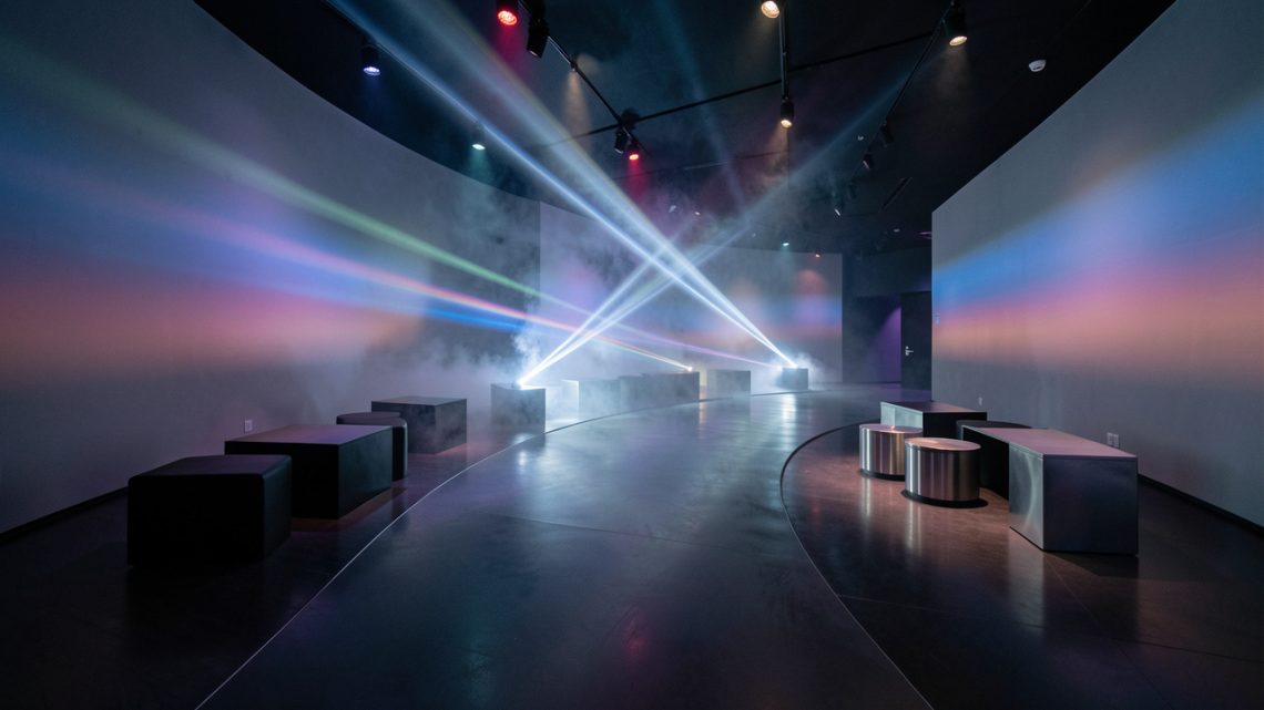 Salle d’exposition immersive élégante, avec parcours au sol, projections lumineuses et mobilier scénographique moderne dans une ambiance cinématographique.