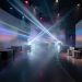 Salle d’exposition immersive élégante, avec parcours au sol, projections lumineuses et mobilier scénographique moderne dans une ambiance cinématographique.