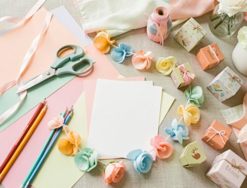 Table colorée de baby shower avec papiers créatifs, matériel de loisirs DIY, guirlandes faites main et petits souvenirs décoratifs sans inscription.