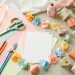 Table colorée de baby shower avec papiers créatifs, matériel de loisirs DIY, guirlandes faites main et petits souvenirs décoratifs sans inscription.