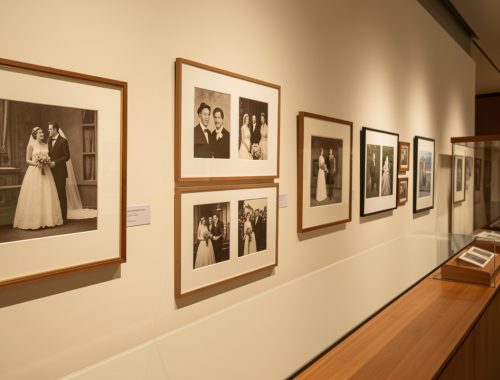 Exposition de photographies anciennes de mariage présentées dans des cadres et vitrines de protection.
